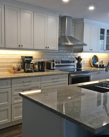 Bright white kitchen with granite island and stainless steel appliances at Hammer Haus II