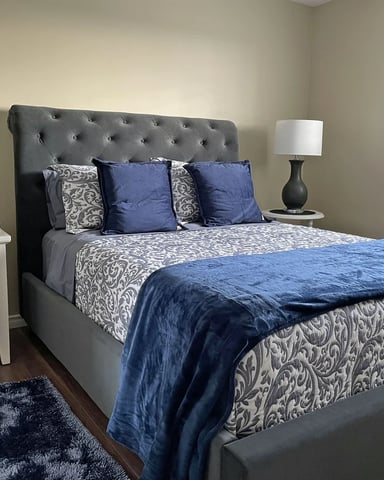 Queen bedroom with tufted headboard and blue bedding at Hammer Haus III