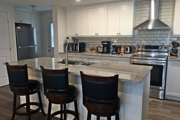 Open-plan kitchen with granite island, bar stools, and stainless steel appliances at Hammer Haus II