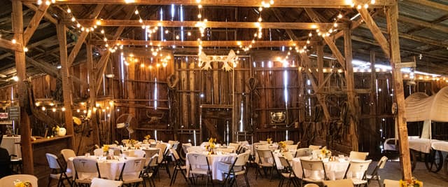 Barn wedding reception with string lights and round tables set for dinner near St. Jacobs