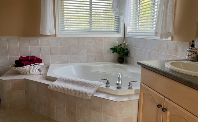 Corner soaker tub with tile surround and window overlooking trees at Hammer Haus