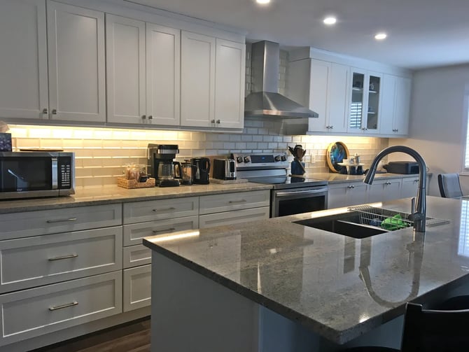 White shaker kitchen with granite island, subway tile backsplash, and stainless appliances at Hammer Haus II