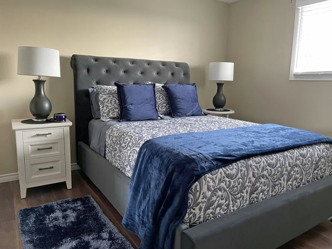 Queen bedroom with tufted grey headboard and navy bedding at Hammer Haus III