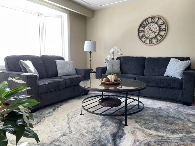 Living room with dark sofas and decorative wall clock at Hammer Haus III