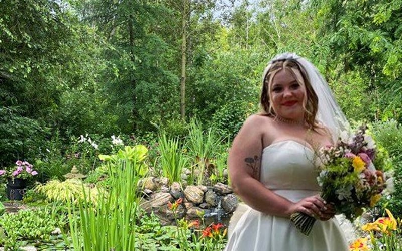 Bride by the pond with waterfall behind her