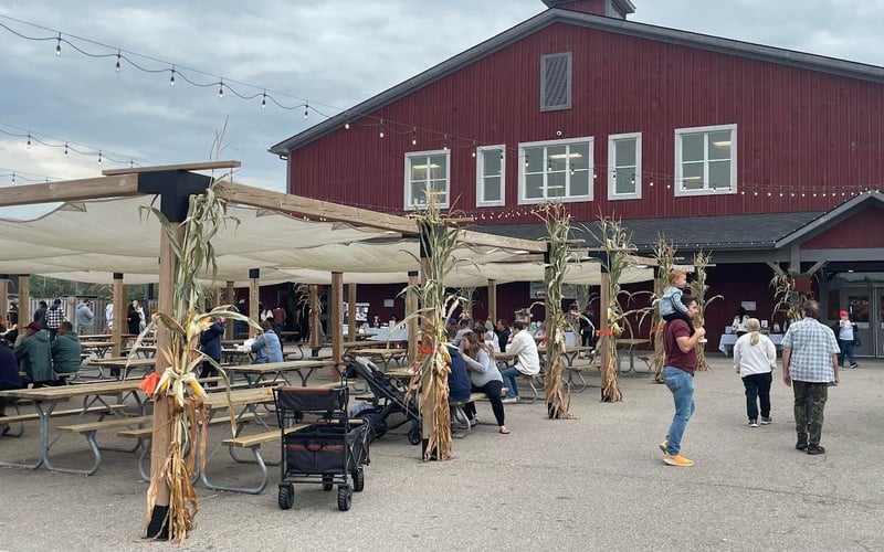 Outdoor eating area with string lights and red barn