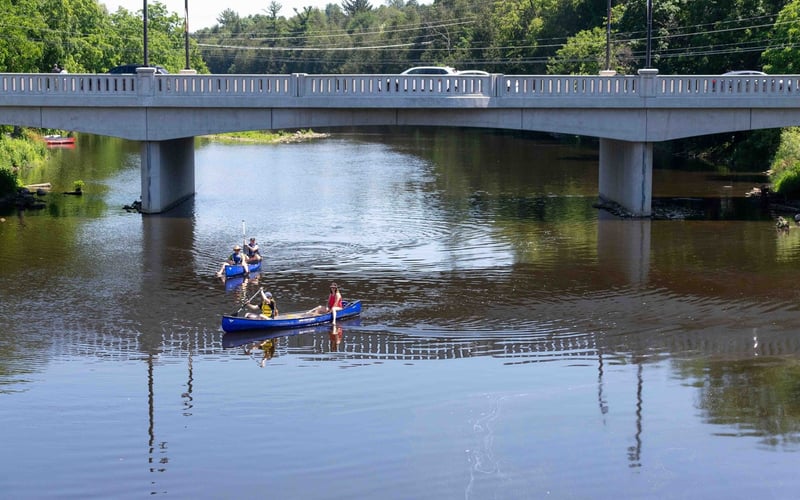 Two blue canoes paddling under the bridge