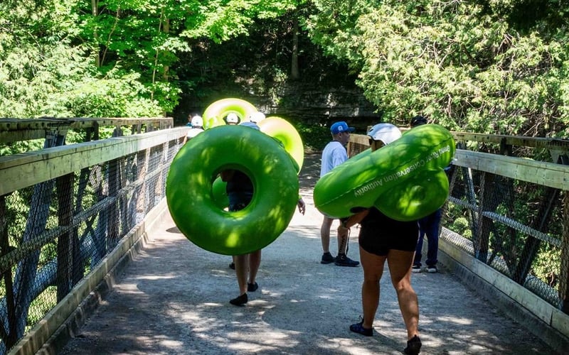People carrying green tubes across a bridge