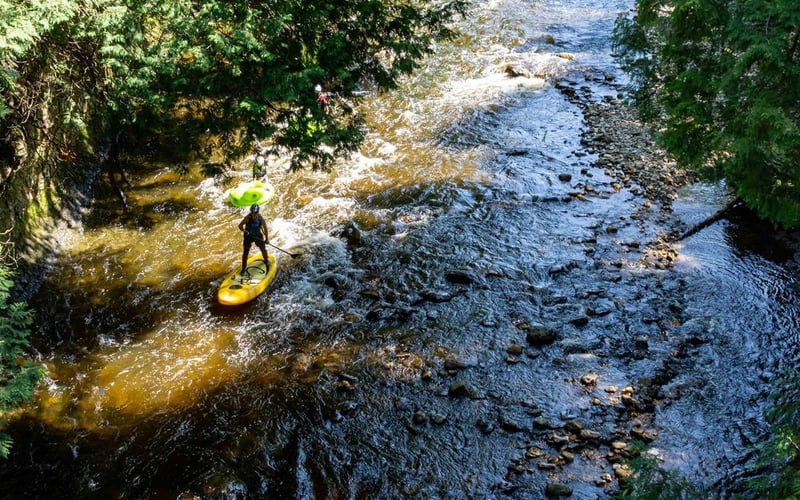 Paddleboarder on wide rocky river