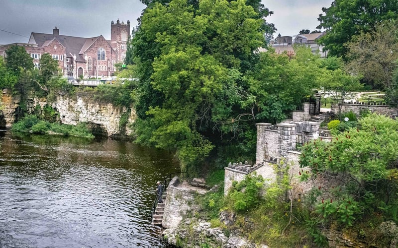 Grand River with stone stairway, castle ruins and church on the bluff, Fergus