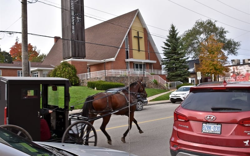 Horse and buggy passing the village church in autumn